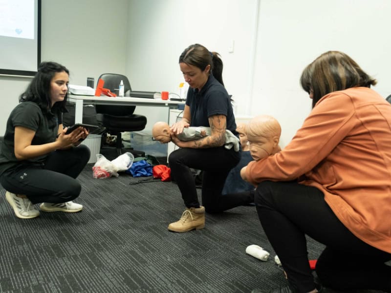 Life Care training participants in infant CPR with mannequins during a first aid class.