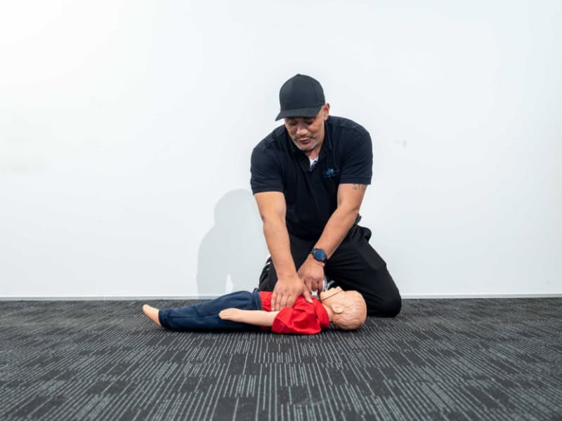 Life Care instructor demonstrating CPR on a child mannequin during first aid training.