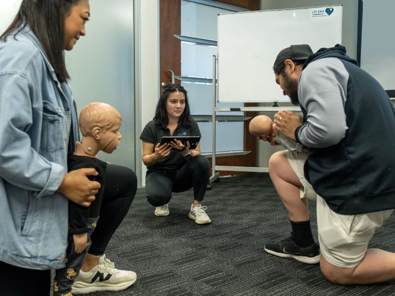 Life Care trainees practicing infant CPR techniques during a first aid training session.