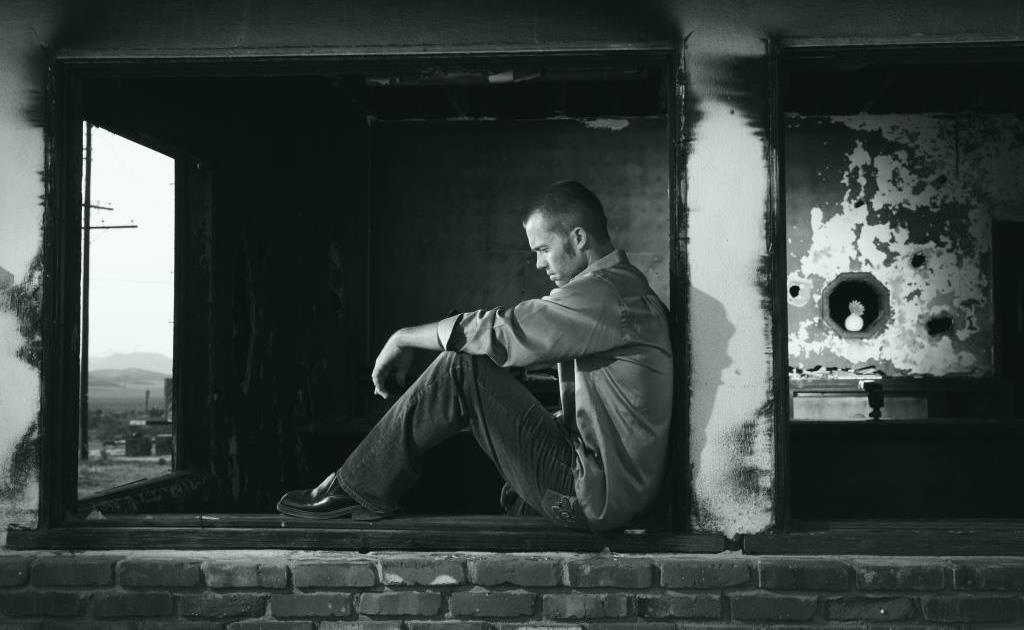 Man sitting alone in a dark room, reflecting on mental health and well-being.