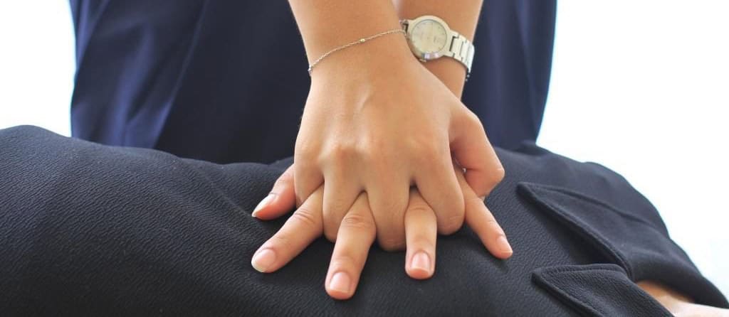 Close-up of hands performing CPR chest compressions during first aid training session.