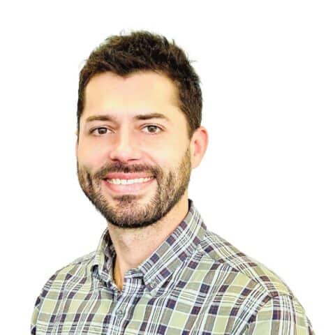 Reuben Turner, Business Development Lead, smiling in a checkered shirt against a white background.