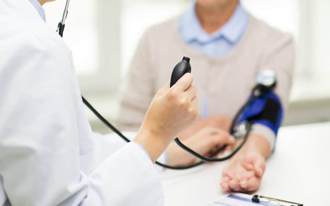 Health consultant measuring blood pressure during a workplace wellness check.