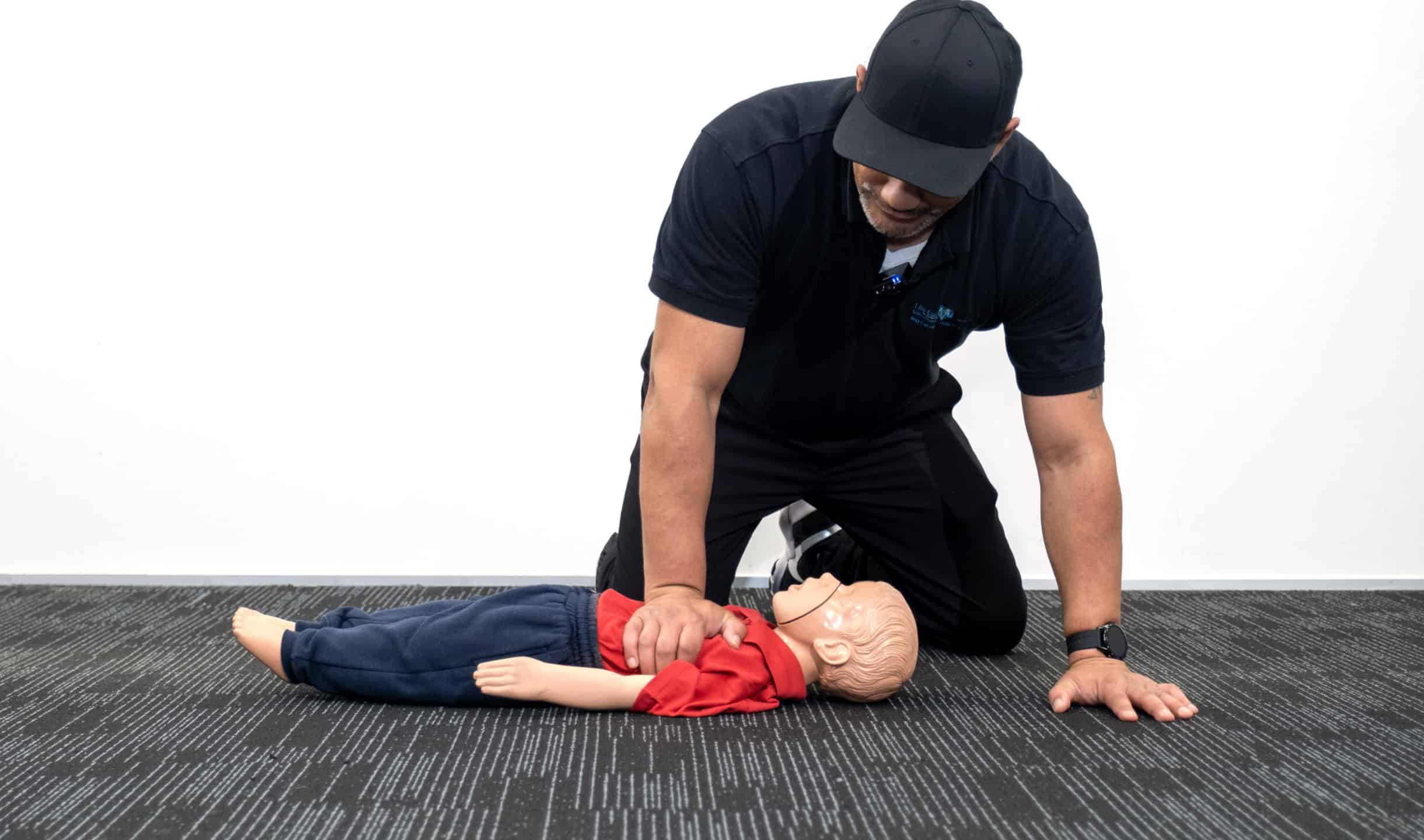 Instructor performing CPR on a child mannequin during a first aid training session.