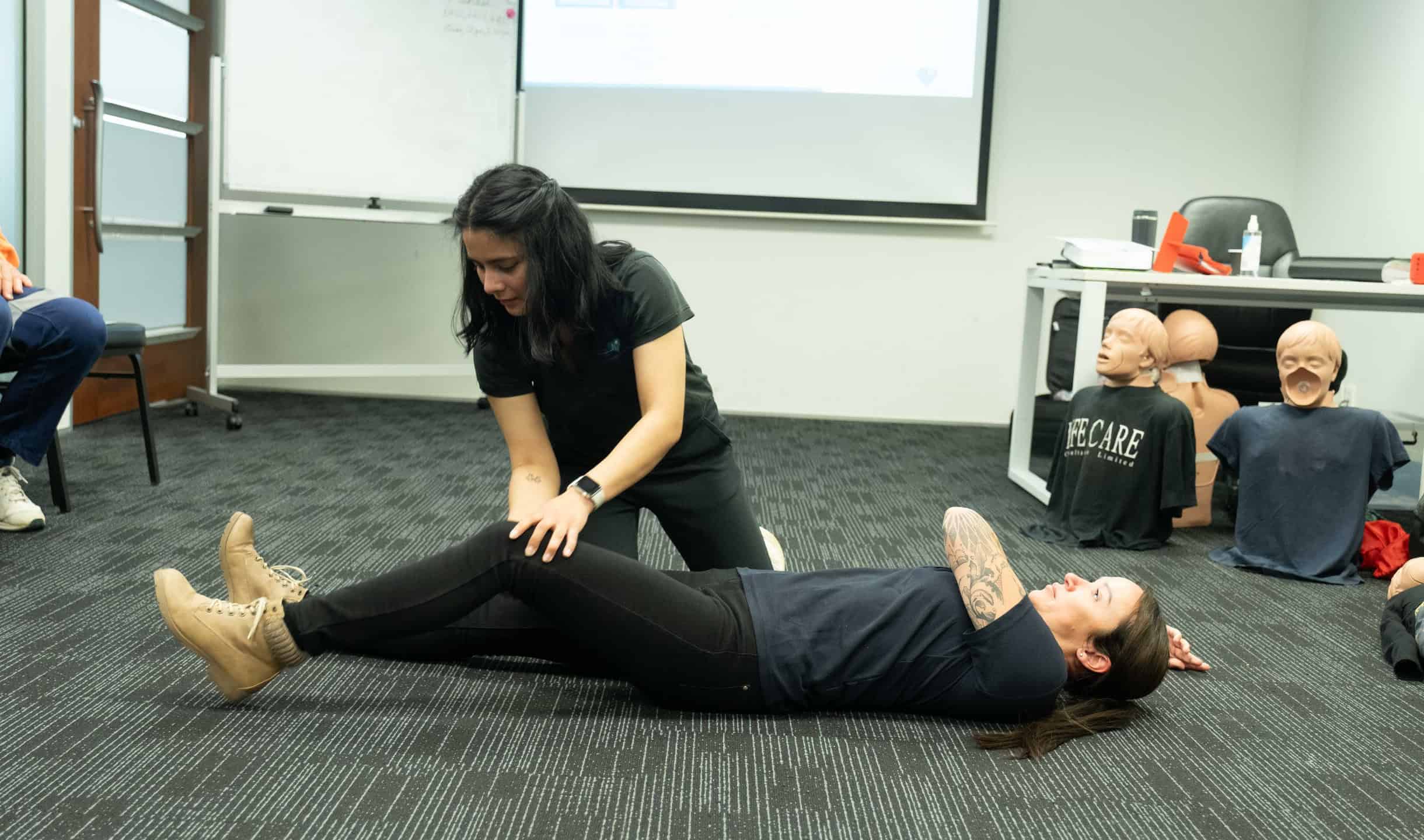 Instructor demonstrating first aid recovery position technique during a training session.