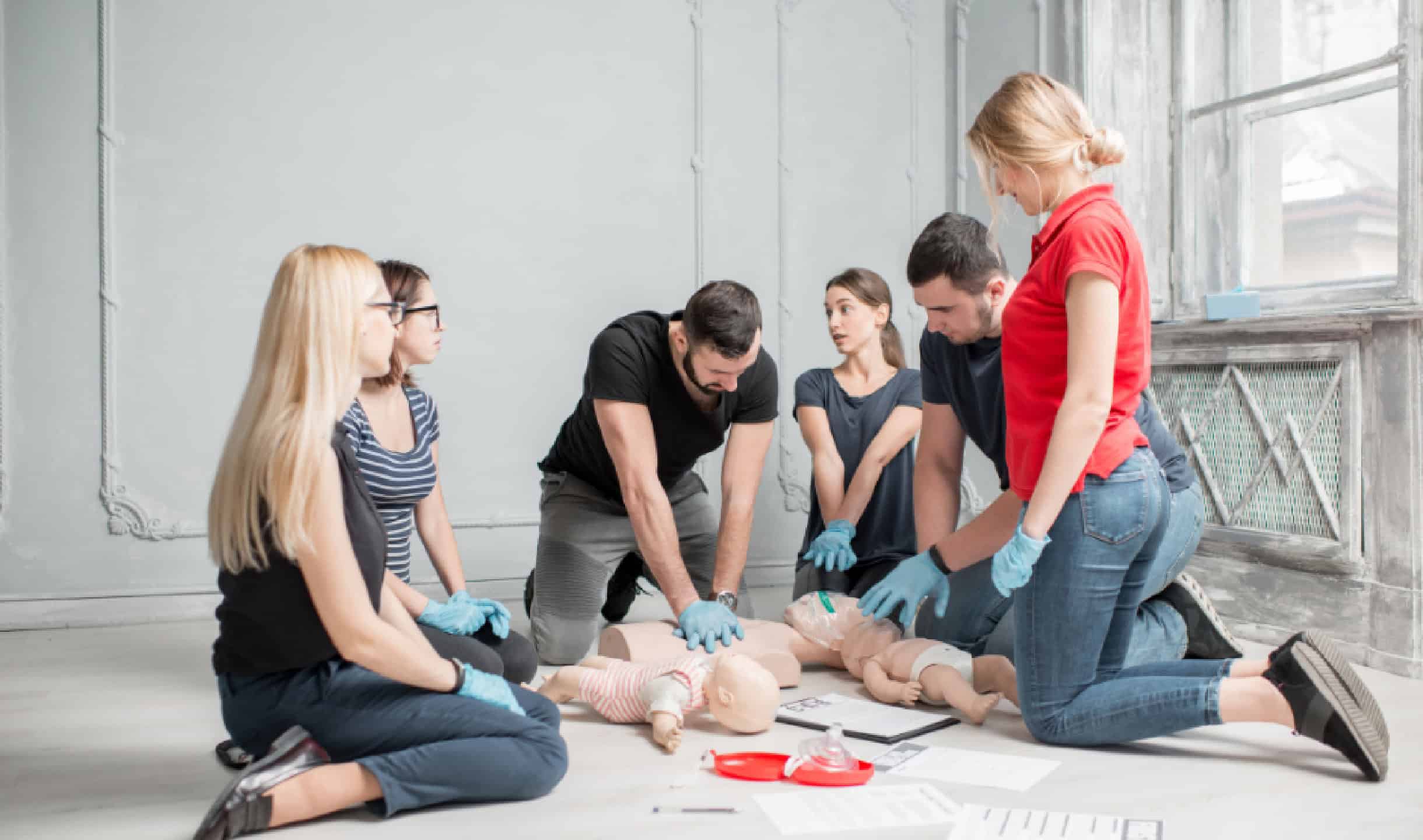 Group of adults practicing CPR on infant mannequins during a first aid training session