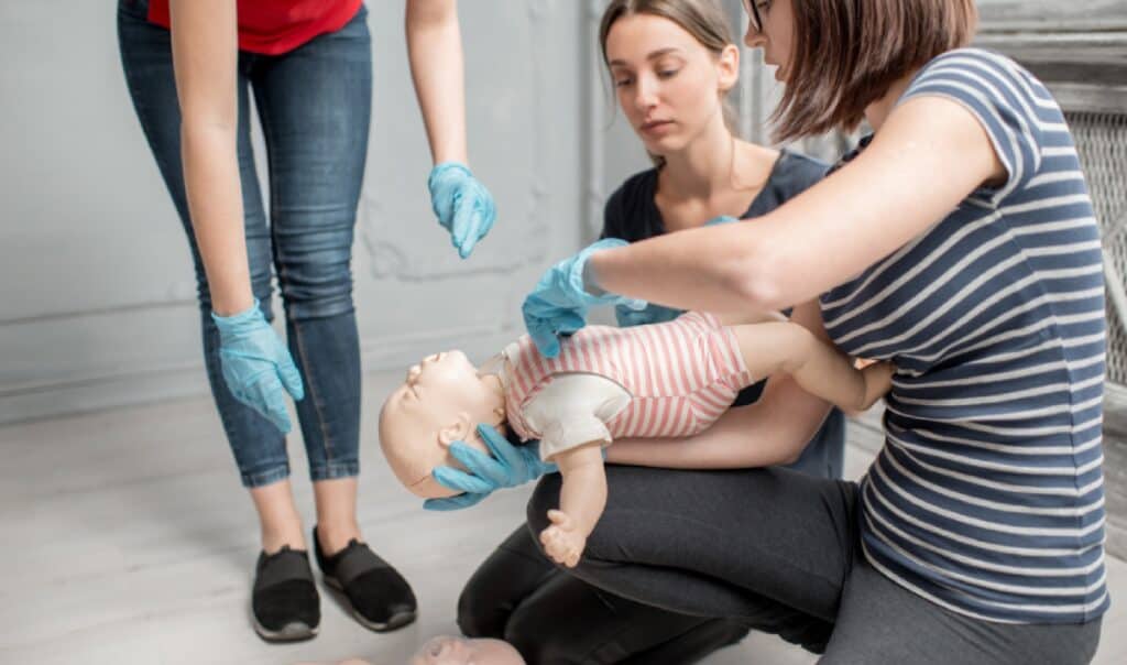 Participants practicing infant CPR techniques using a manikin during a first aid training session.