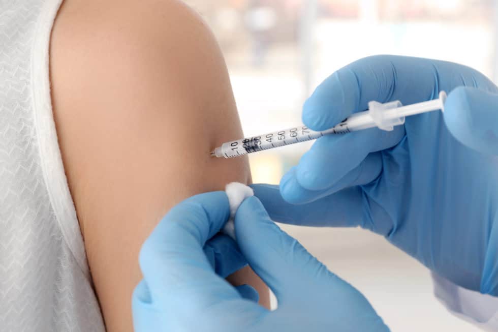 Healthcare professional administering a vaccine injection into a patient's arm.